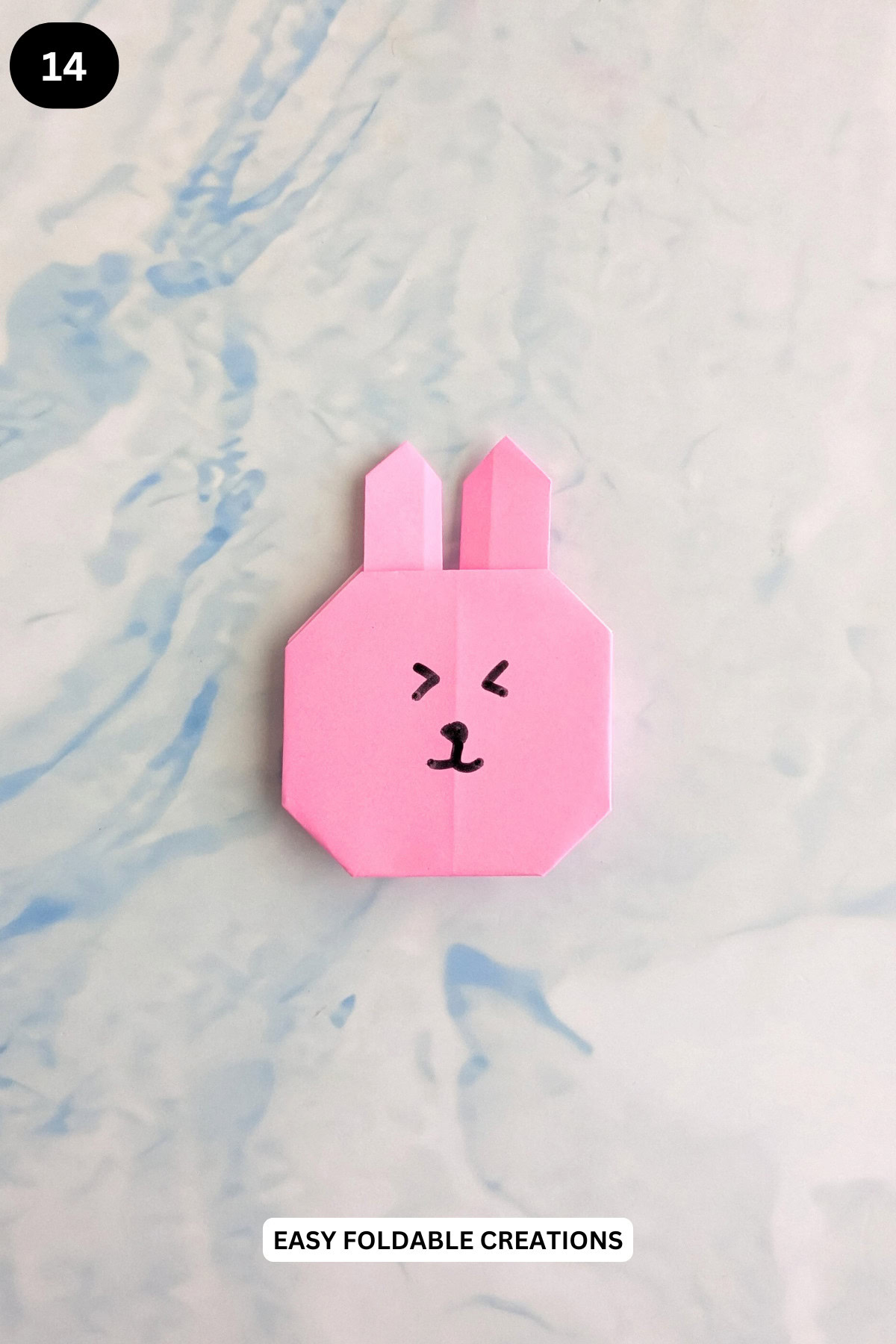 Step 14 for folding an origami rabbit face.