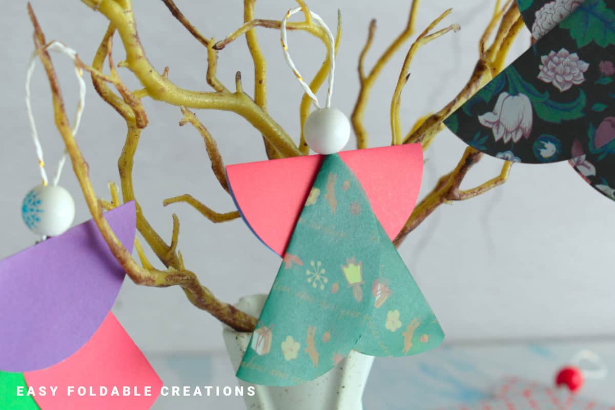 Close up image of a paper angel hanging on a tree.
