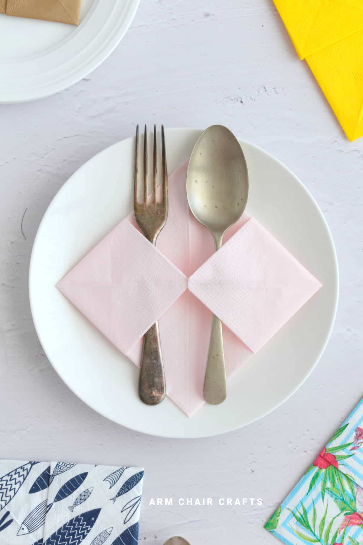 Folded napkin on a plate with cutlery.